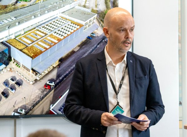 Mann står foran en skjerm med bilde av et datasenter