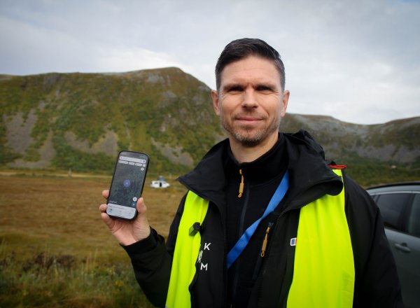 Espen Slette står med gul refleksvest og holder opp telefonen sin hvor han er inne på Google Maps