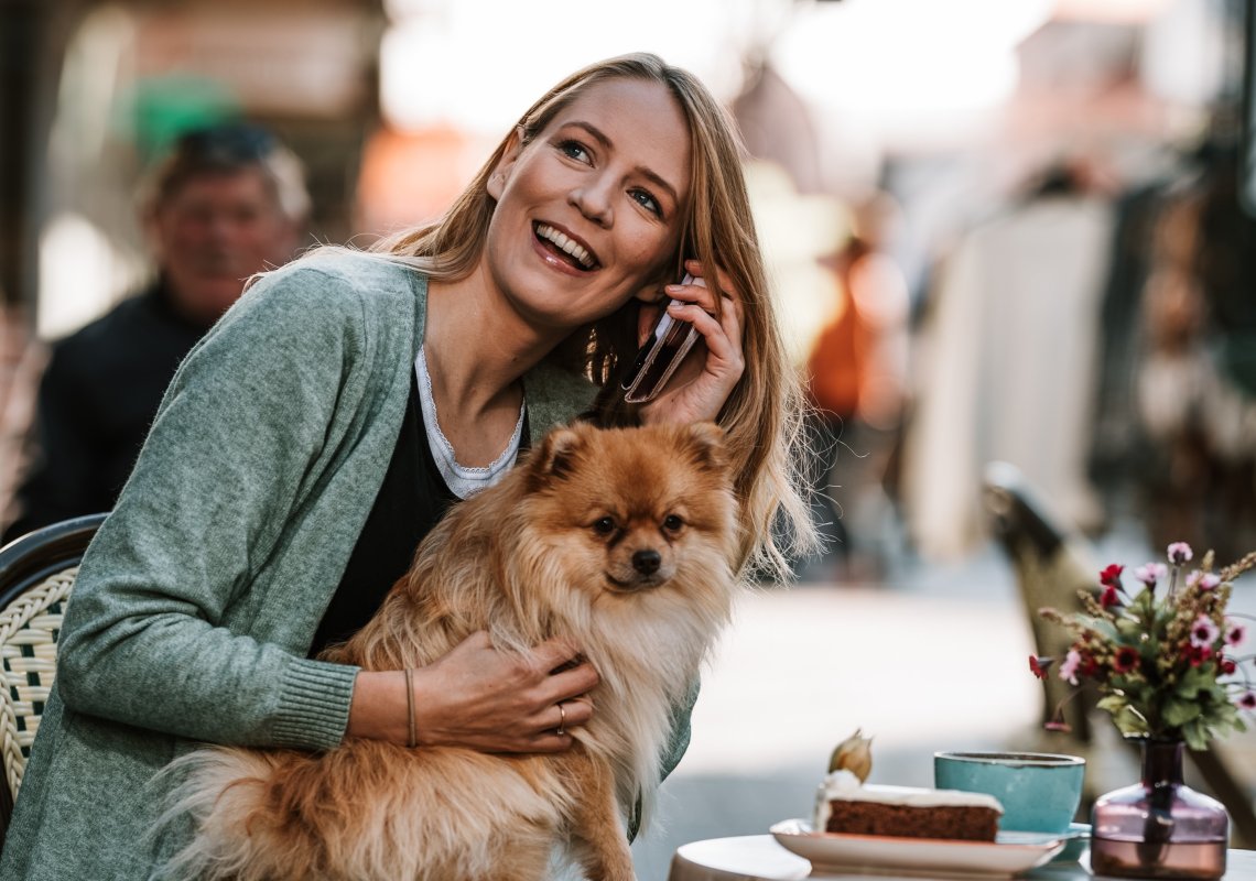 Dame på cafe med mobil og hund