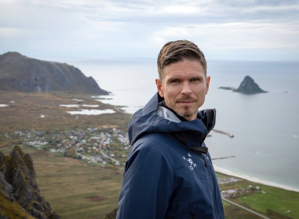 En mann står på toppen av et fjell og stirrer inn i kamera