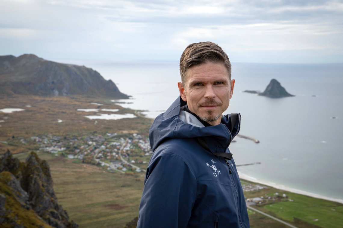 En mann står på toppen av et fjell og stirrer inn i kamera