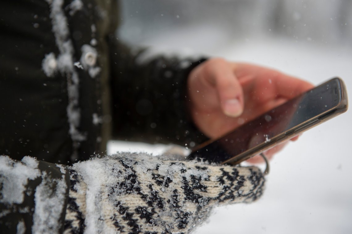 Mann ser på mobil i snøvær