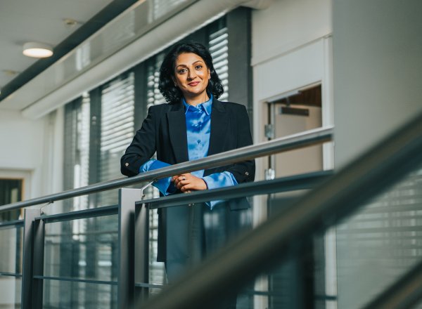 Avdelingsdirektør Kamilla i Sharma står ved et gelender i et glassbygg.