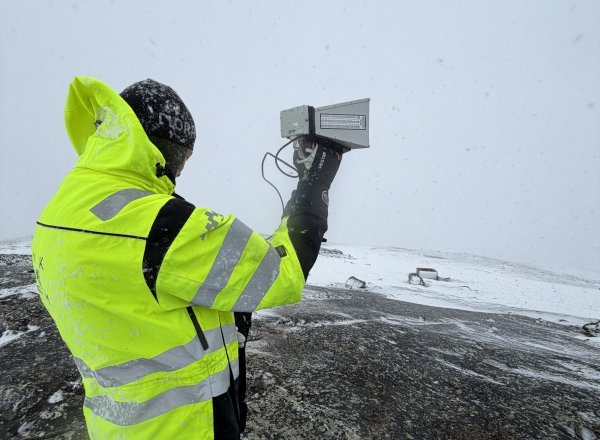 Bildet viser en Nkom-ansatt som står med måleutstyr i Øst-Finnmark.