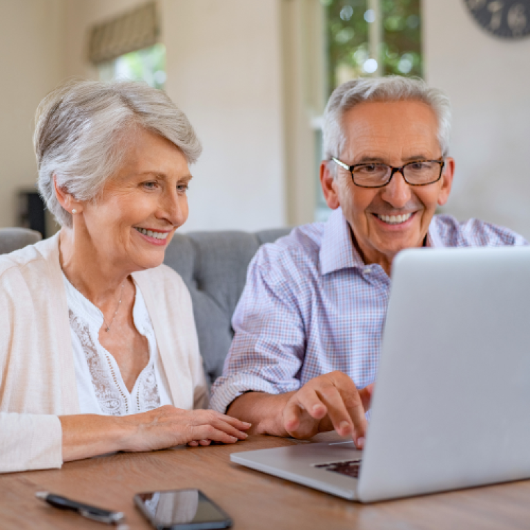 Eldre ektepar som sitter med en PC